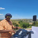 DJ SouthLAnd performing outdoors with scenic hills behind him.
