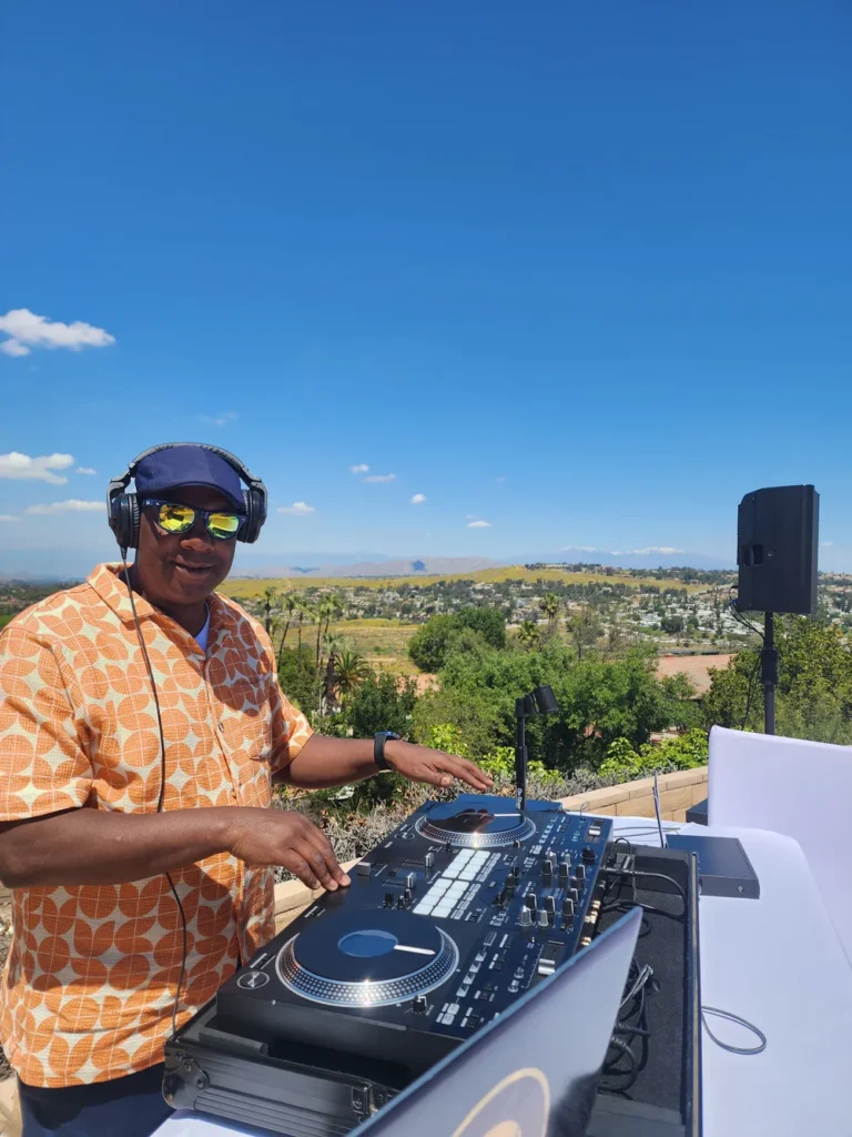 DJ SouthLAnd performing outdoors with scenic hills behind him.